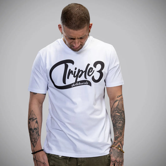 A man wearing a white short-sleeve t-shirt with a black 'Triple 3 skateboard' graphic on the chest, photographed against a neutral gray background.